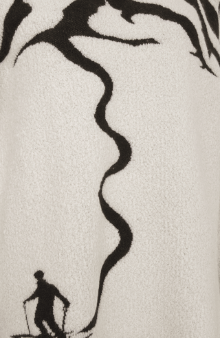 Detailansicht eines Damenpullovers aus 100 % extrafeiner Merinowolle, Modell „Chatel-ME“ in der Farbe Weiss. Die Vorderseite zeigt ein kunstvoll gestaltetes Jacquard-Motiv aus skizzierten Berglandschaften, urbanen Elementen und dynamischen Skifahrern. Das hochwertige Merinogarn – leicht, weich und angenehm auf der Haut – wird in Italien produziert und auf modernsten Maschinen verarbeitet. Die Kombination aus künstlerischem Design & technischer Strickkunst macht den Pullover besonders stilvoll