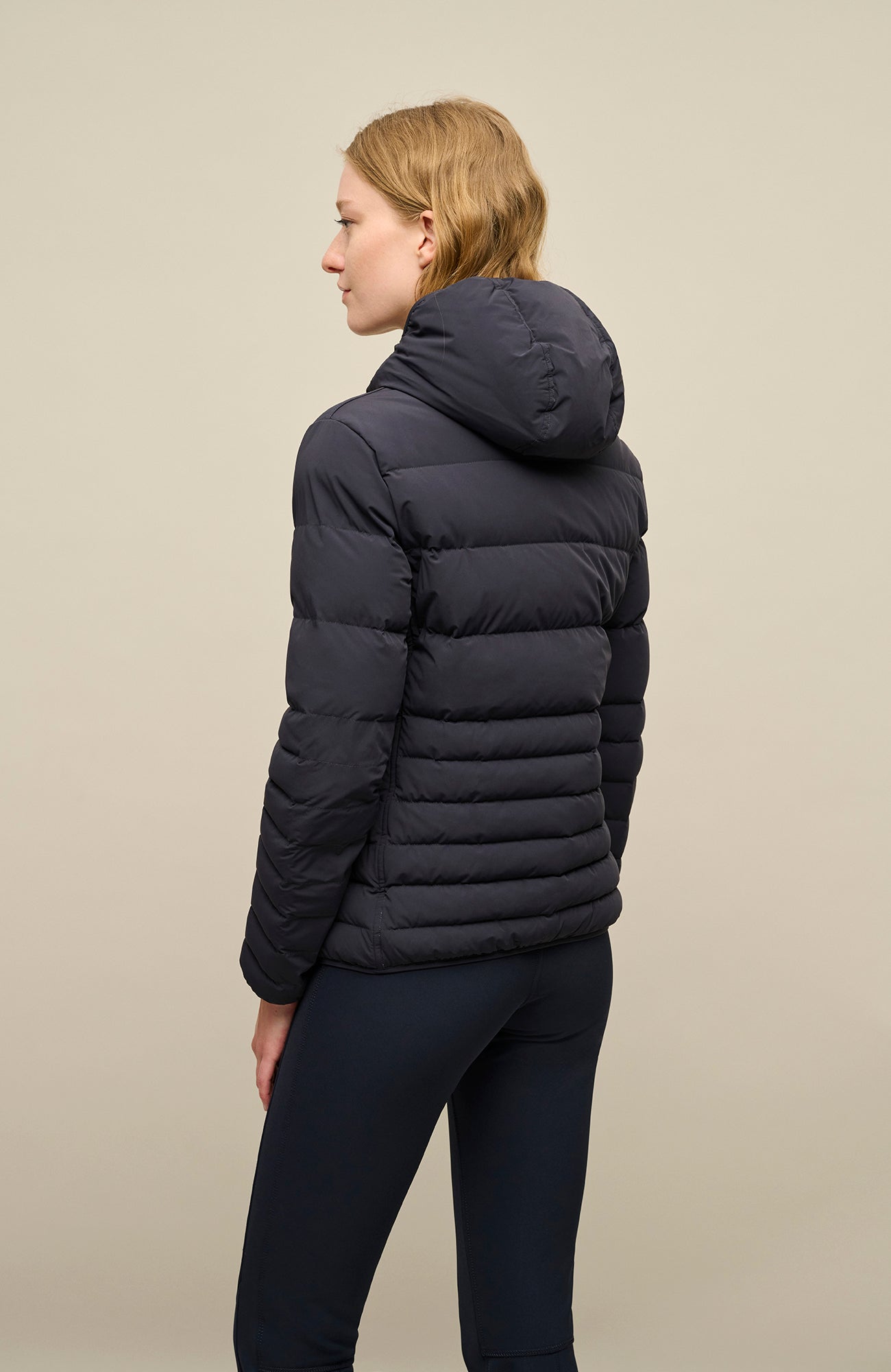 Rückansicht der Frauenschuh Damen-Winterjacke „Leonora“ (Modell STN 1630) in der Farbe Midnight (dunkles Blau), getragen von einem weiblichen Model. Die Jacke zeigt einen geraden Schnitt mit sportlich-elegantem Design, gefertigt aus wasserabweisendem, atmungsaktivem, feuchtigkeitsregulierendem, elastischem und wärmendem Material. Ideal für Wintersport und Freizeit.