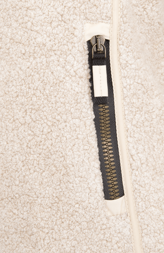 Detailaufnahme der Seitentasche der Damenjacke „WERA-CT 94-0“ von Frauenschuh in der Farbe „Caramel“, einem warmen Creme-Beige. Die Tasche ist in das weiche, luxuriöse Teddyfleece mit Kaschmiranteil eingearbeitet und verfügt über einen feinen, gut vernähten Reißverschluss in passender Farbe. Die flauschige Struktur des Materials ist deutlich erkennbar, die Nahtführung sauber und präzise gearbeitet. Die Tasche ist funktional und dezent gestaltet, passend zum sportlich-eleganten Design der nachhaltigen Jacke