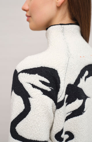 Vorderansicht eines Damenpullovers aus 100 % extrafeiner Merinowolle, Modell „Chatel-ME“ in der Farbe Grau. Die Vorderseite zeigt ein kunstvoll gestaltetes Jacquard-Motiv aus skizzierten Berglandschaften, urbanen Elementen und dynamischen Skifahrern. Das hochwertige Merinogarn – leicht, weich und angenehm auf der Haut – wird in Italien produziert und auf modernsten Maschinen verarbeitet. Die Kombination aus künstlerischem Design & technischer Strickkunst macht den Pullover besonders stilvoll
