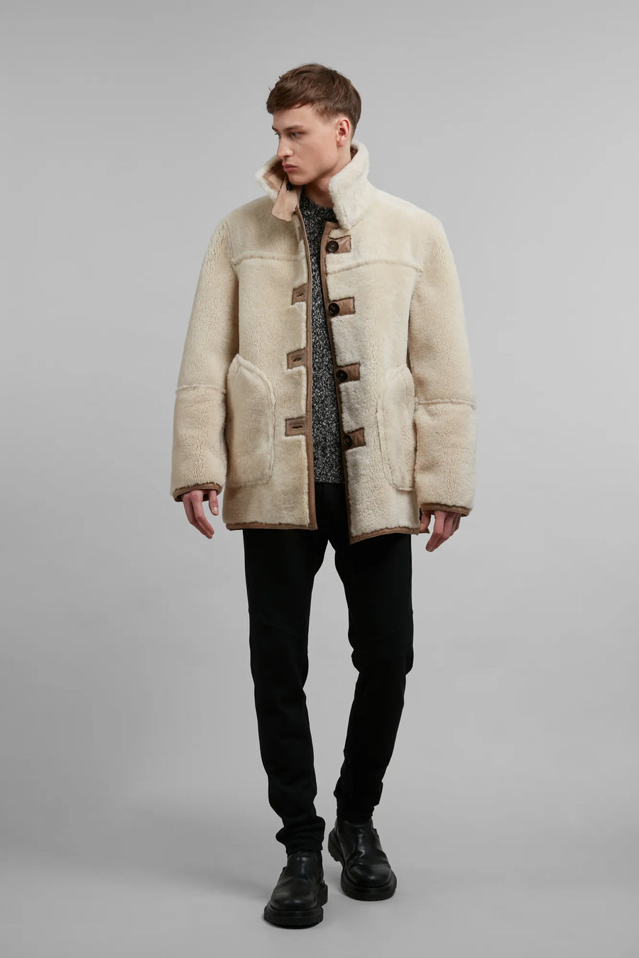 Der wendbare Lammfellmantel Fin-MV verbindet außergewöhnliche Vielseitigkeit mit luxuriöser Wärme und wird mit dem Strickpullover Glenn aus feinster schottischer Schurwolle und der Hose Collin zu einem Look von zeitloser, alpiner Eleganz.