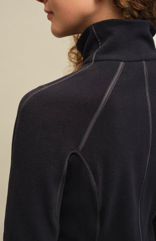 Von einem Model getragen. Detailansicht der Damen Fleecejacke Wera-BF in der Farbe Midnight von Frauenschuh, nachhaltig produziert. Nahaufnahme des hochwertigen Materials, des Zwei-Wege-Reißverschlusses und des modernen Designs, das Komfort und Flexibilität für Frühling und Sommer bietet