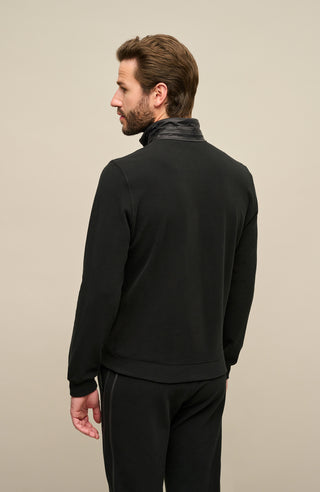 Rückansicht der Herrenjacke „Oliver-BF 01-0“ von Frauenschuh in klassischem Schwarz. Die Jacke besticht durch ihre schlichte, funktionale Rückseite mit ergonomischem Schnitt und dezenter Taillierung. Der hohe Stehkragen sowie die klar gesetzten Rückennähte betonen die strukturierte Form. Das Material ist glatt, leicht technisch und wirkt hochwertig. Der Artikel wird von einem Model getragen