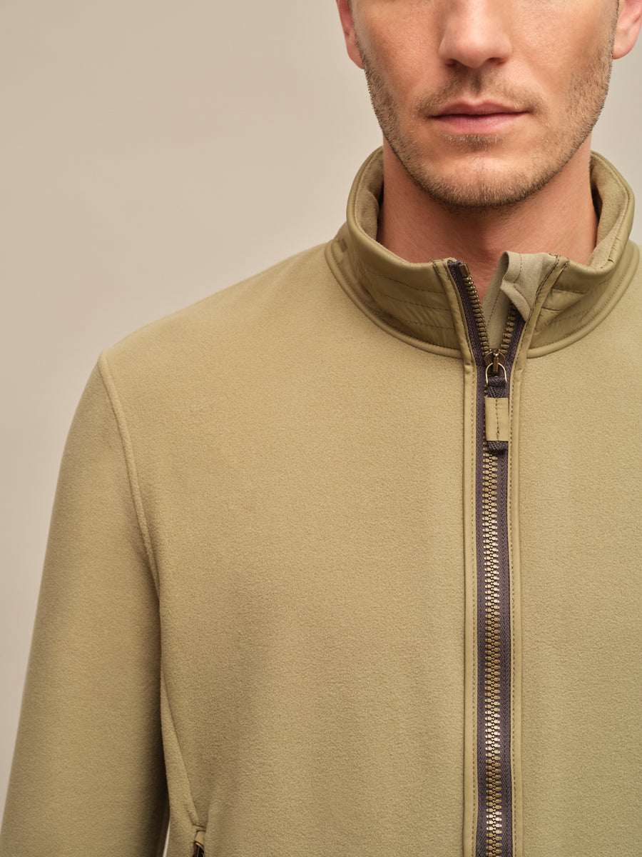 Detailansicht der Herrenjacke „Oliver-BF 2680“ in der Farbe „Sage“ aus der Frühjahrs- und Sommerkollektion von Frauenschuh. Zu sehen ist ein hochwertig verarbeiteter Abschnitt der Jacke – beispielsweise der Reißverschluss. Feine Nahtverläufe, saubere Verarbeitung und das matte, leicht strukturierte Material werden deutlich sichtbar. Die Farbe „Sage“ – ein edles, graugrünes Pastell – bringt die dezente Eleganz des Designs zur Geltung