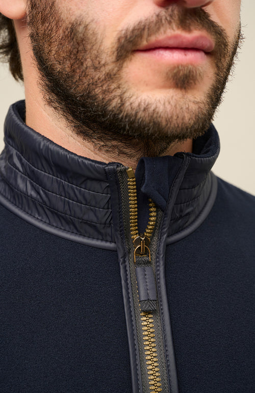 Detailansicht der Herrenjacke „Oliver BF 163-0“ von Frauenschuh in der Farbe „Midnight“, einem tiefen Dunkelblau. Die Nahaufnahme zeigt präzise Verarbeitungsdetails, einen Reißverschluss und den Kragen. Das hochwertige Material wirkt glatt, leicht strukturiert und funktional. Die Aufnahme betont die exzellente Handwerkskunst, die klare Linienführung und das minimalistische Design der Jacke – ideal für anspruchsvolle Träger