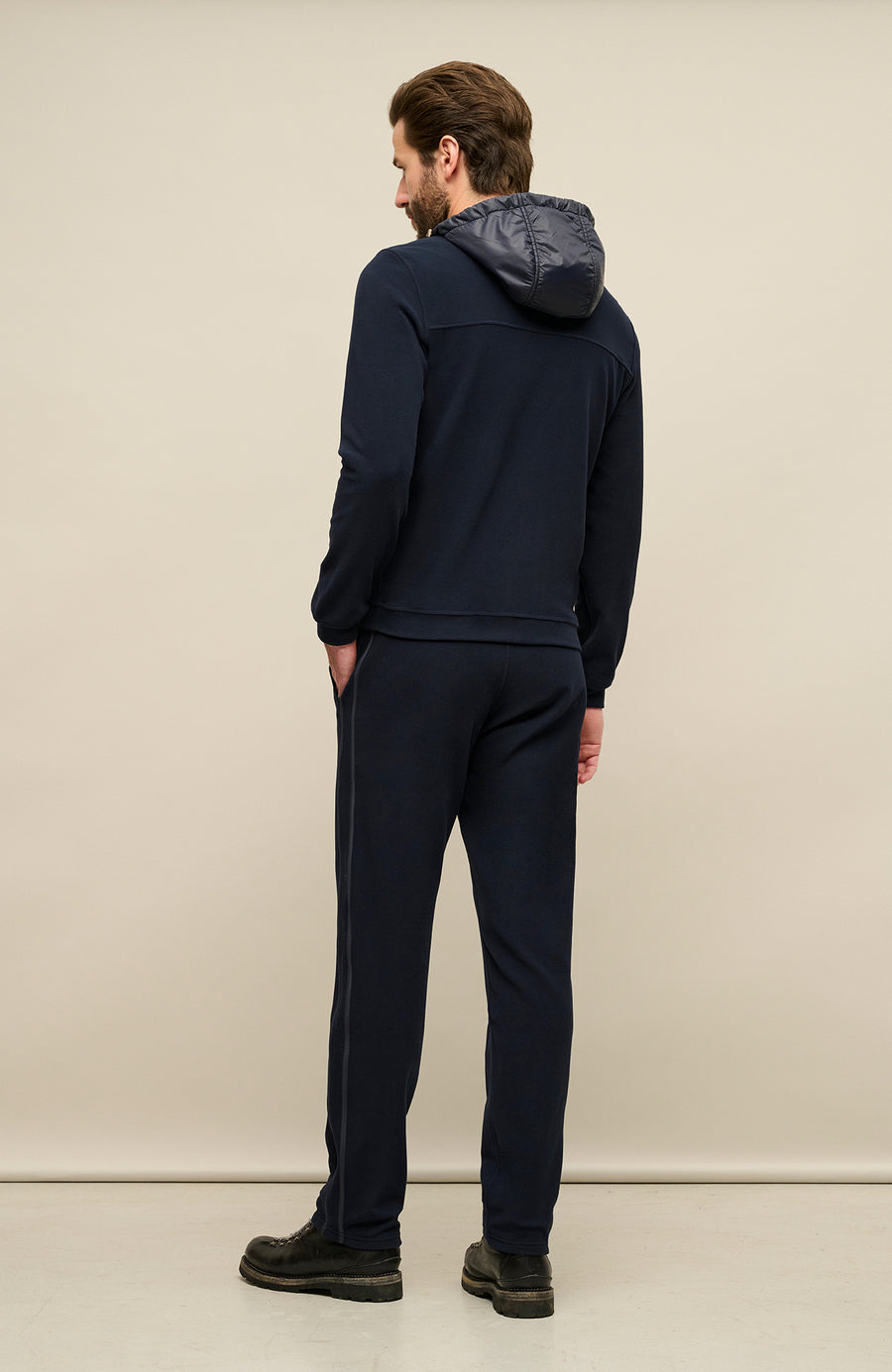 Rückansicht der Herrenjacke „Thomas“ von einem Model getragen in Dunkelblau (1630 Midnight). Die Jacke aus nachhaltigem Biodegradable Fleece zeigt den minimalistischen Schnitt, den verstellbaren Nylon-Kapuzenkragen und den Zweiwegereißverschluss, ideal für alle Jaheszeiten