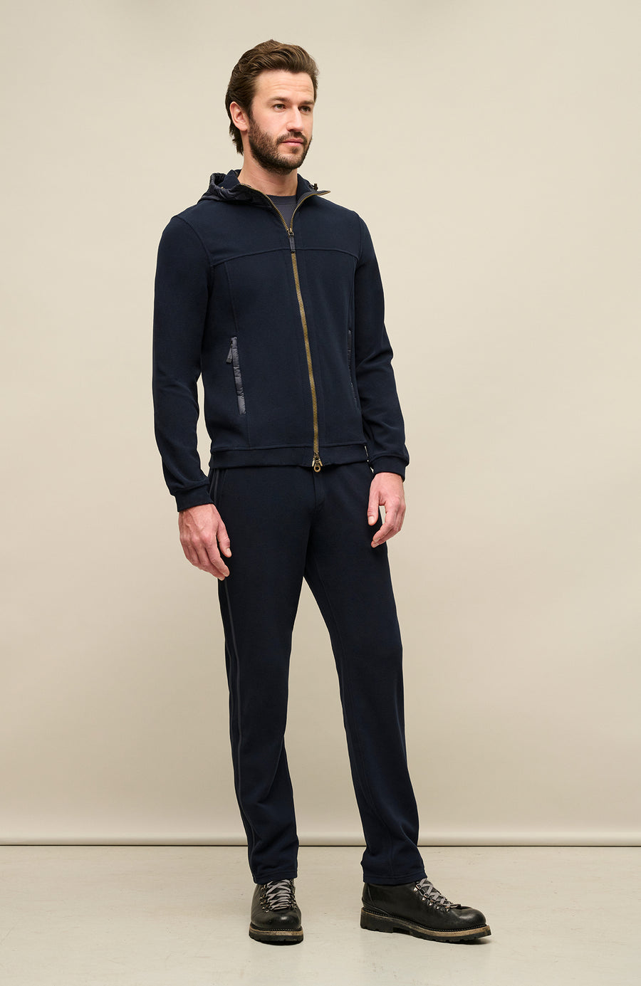 Seitenansicht der Herrenjacke „Thomas“ von einem Model getragen, in der Farbe dunkelblau (1630 Midnight), gefertigt aus umweltfreundlichem Biodegradable Fleece. Die Jacke verfügt über einen minimalistischen Schnitt, einen verstellbaren Nylon-Kapuzenkragen, praktische Reißverschlusstaschen und einen Zweiwegereißverschluss