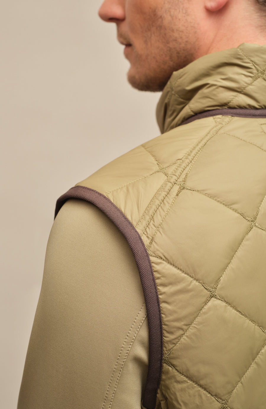 Detailaufnahme der gesteppten Herrenweste „Henri-QL“ von Frauenschuh in Sage (Grün); Fokus auf das hochwertige, leicht glänzende Nylonmaterial mit präziser Rautensteppung; sichtbar sind feine Verarbeitung, glatte Kantenabschlüsse und dezente Nahtverläufe; ein Ausschnitt des Kragens im Bild; die Aufnahme betont die exklusive Materialqualität und das edle Finish der Sommer- und Frühlingsweste aus der Frauenschuh-Kollektion