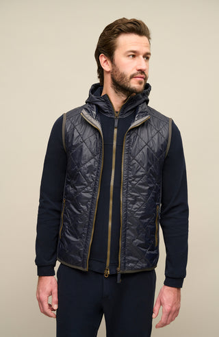 Model trägt die Damen-Quiltweste „Henri-QL“ von Frauenschuh in Midnight (dunkelblau); elegante, rautenförmig gesteppte Weste aus leichtem, hochwertigem Nylonmaterial; taillierte Passform für eine feminine Silhouette; ausgestattet mit einem sportlich-eleganten Stehkragen und Zwei-Wege-Reißverschluss; ideal für Übergangszeiten wie Frühling und Sommer; das Model steht frontal zur Kamera und präsentiert die moderne, funktionale Outdoor-Weste