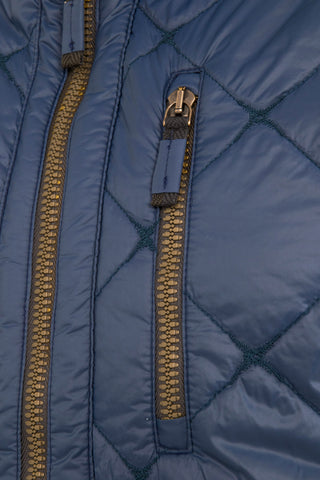 Detailansicht der Herren-Quiltweste „LucasMulti-QL“ von Frauenschuh in Alaska Blue; im Fokus steht die links platzierte Brusttasche mit dezentem, nahtfeinem Reißverschluss sowie der zentrale, hochwertige Zwei-Wege-Frontzip; das leicht glänzende Nylonmaterial ist in markanter Rautensteppung ausgeführt; die feine Verarbeitung, die Ton-in-Ton-Nähte und die technische Ästhetik unterstreichen den luxuriösen, funktionalen Anspruch der Weste – ideal für stilvolle Übergangslooks im Frühling und Sommer