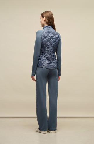 Model trägt die Damen-Powerstretch-Hose „Inga“ in der Farbe Denim – Rückansicht, zeigt die gerade geschnittene Hose ohne Taschen und Reißverschlüsse, mit elastischem Bund und schlichtem Design, das für maximale Bewegungsfreiheit und Tragekomfort sorgt