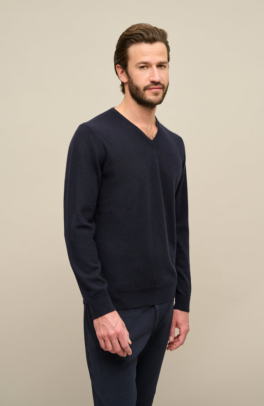 Ein männliches Model trägt den Kaschmirpullover „Nio2.0-WS“ von Frauenschuh in der Farbe Midnight (Dunkelblau); das luxuriöse, weiche Kaschmirmaterial verleiht dem Hoodie eine edle Haptik und optimale Wärme für Herbst und Winter; der Pullover hat einen feinen Rippenstrick an Saum und Ärmelabschlüssen
