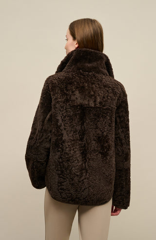 Damen Lammfellcape Modell Dolli in der Farbedunkelbraun Model Rueckansicht Fellseite – edles Cape aus weichem Lammfell mit fließendem Schnitt, stilvoll und wärmend für die kalte Jahreszeit.“
