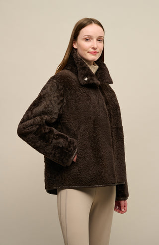 Damen Lammfellcape Modell Dolli in der Farbe dunkelbraun Modelansicht Fellseite vorne – edles Cape aus weichem Lammfell mit fließendem Schnitt, stilvoll und wärmend für die kalte Jahreszeit.“