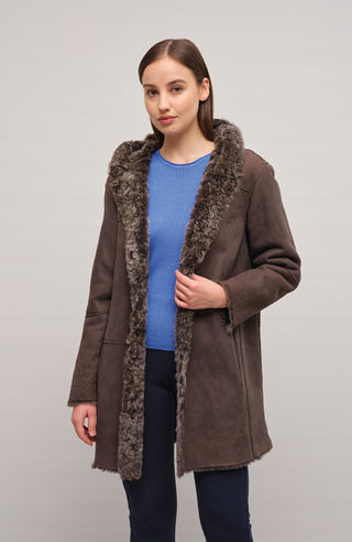 Damen Lammfellmantel mit Kapuze von Frauenschuh, Modell Olivera in der Farbe dunkelbraun Model Vorderansicht– luxuriöser Wintermantel aus hochwertigem Lammfell für stilvolle Wärme.