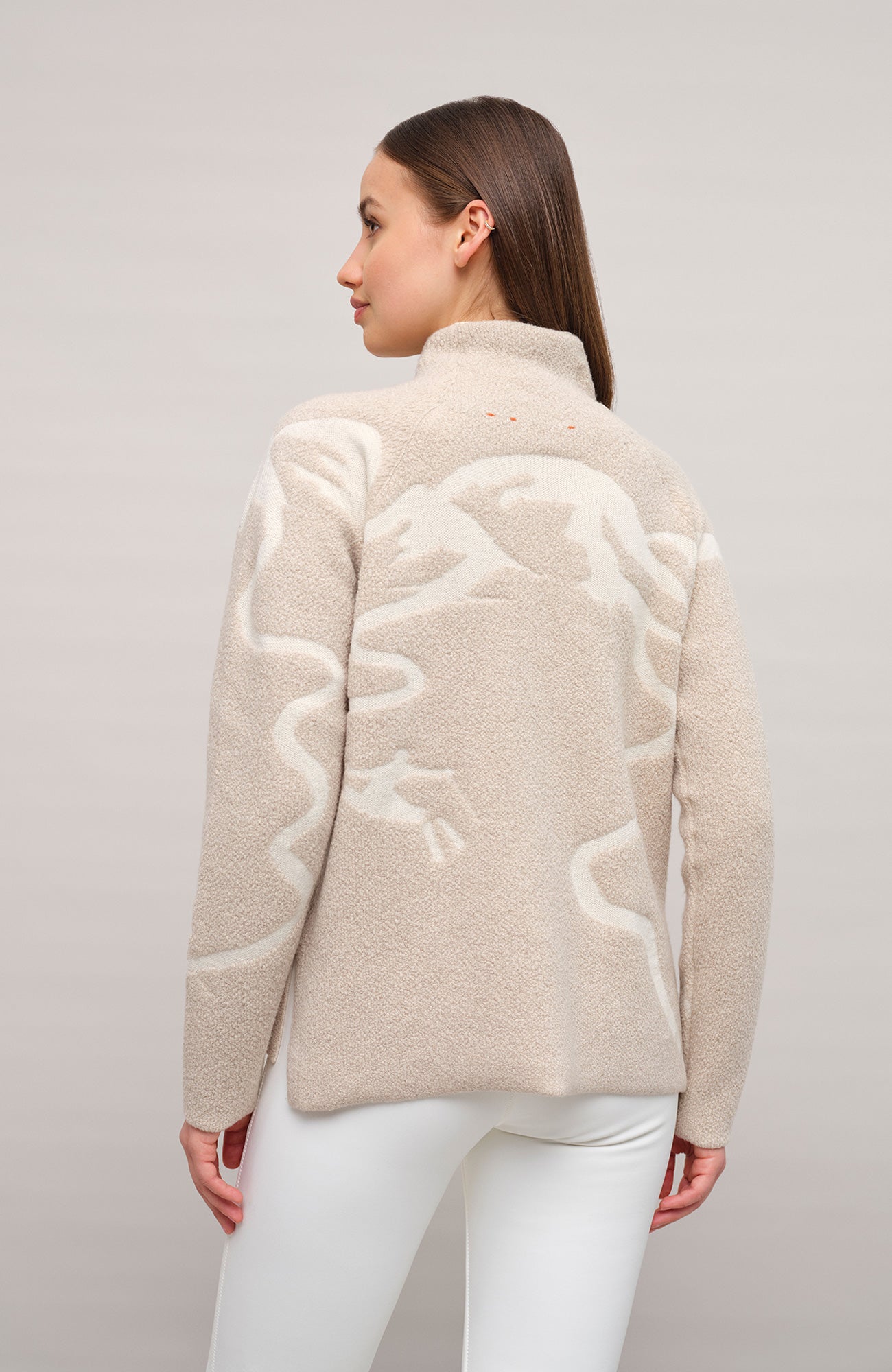 Vorderansicht eines Damenpullovers aus 100 % extrafeiner Merinowolle, Modell „Chatel-ME“ in der Farbe Beige. Die Vorderseite zeigt ein kunstvoll gestaltetes Jacquard-Motiv aus skizzierten Berglandschaften, urbanen Elementen und dynamischen Skifahrern. Das hochwertige Merinogarn – leicht, weich und angenehm auf der Haut – wird in Italien produziert und auf modernsten Maschinen verarbeitet. Die Kombination aus künstlerischem Design & technischer Strickkunst macht den Pullover besonders stilvoll