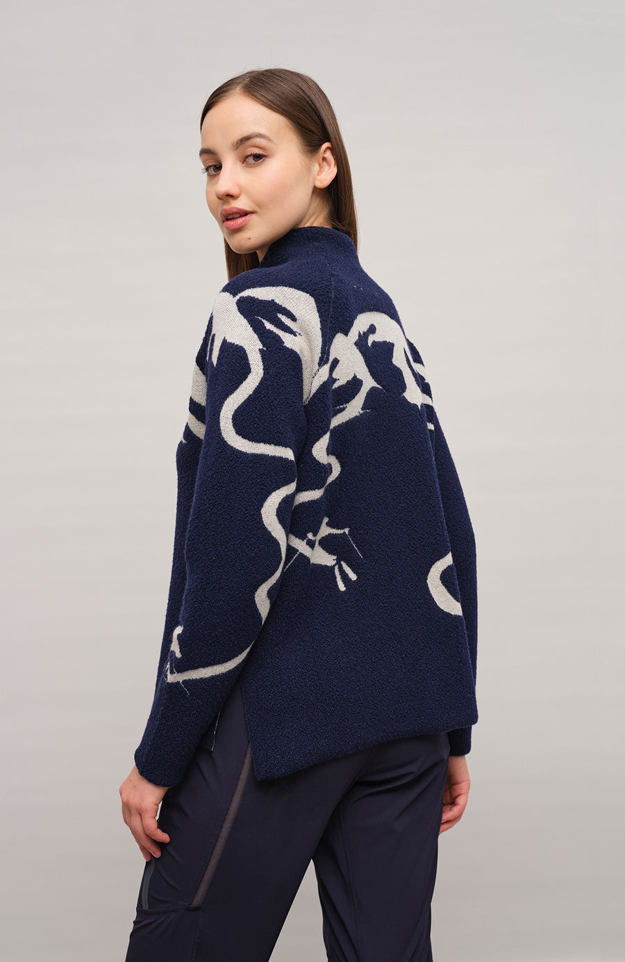 Vorderansicht eines Damenpullovers aus 100 % extrafeiner Merinowolle, Modell „Chatel-ME“ in der Farbe Dunkelblau. Die Vorderseite zeigt ein kunstvoll gestaltetes Jacquard-Motiv aus skizzierten Berglandschaften, urbanen Elementen und dynamischen Skifahrern. Das hochwertige Merinogarn – leicht, weich und angenehm auf der Haut – wird in Italien produziert und auf modernsten Maschinen verarbeitet. Die Kombination aus künstlerischem Design & technischer Strickkunst macht den Pullover besonders stilvoll