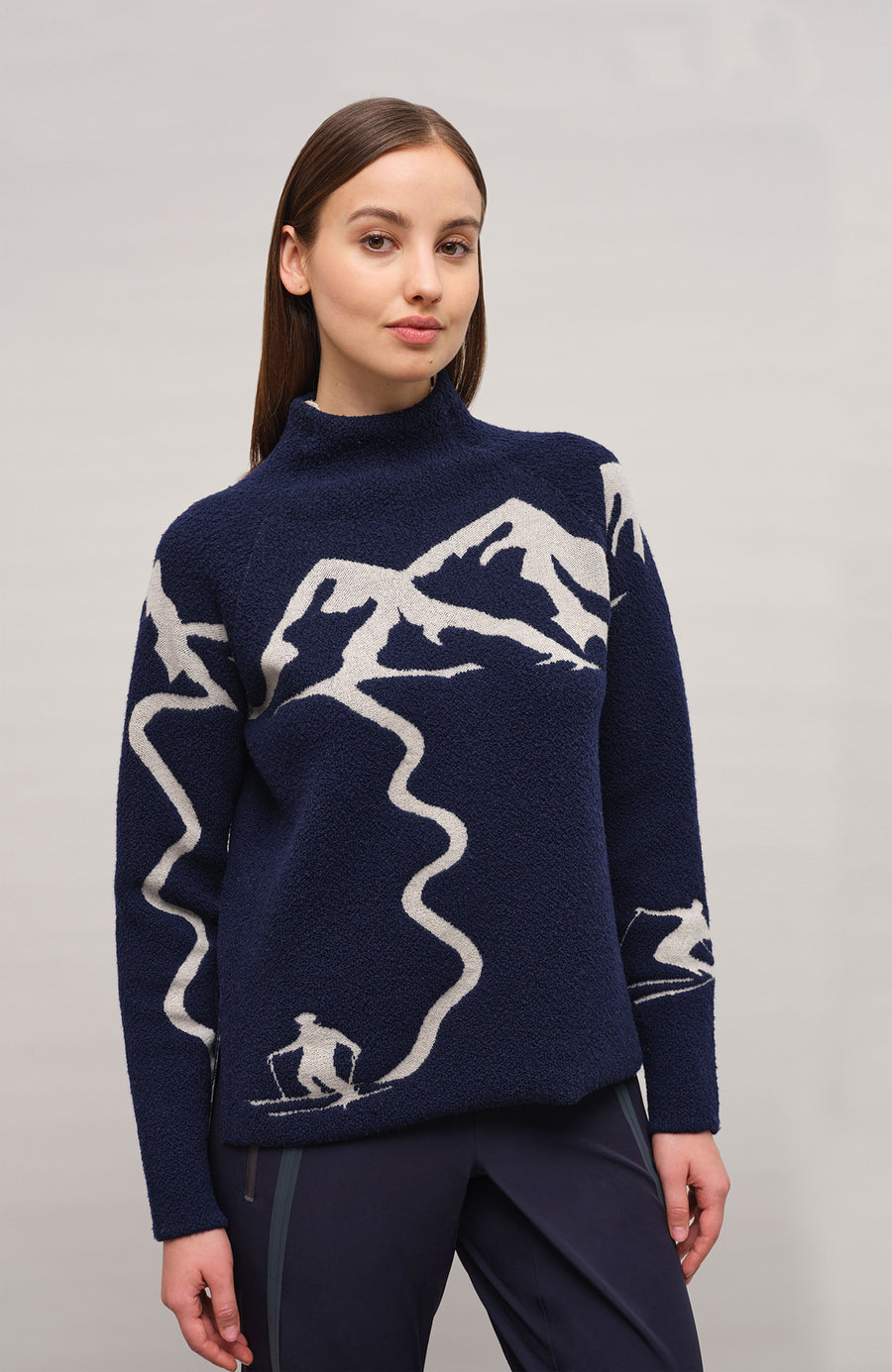 Vorderansicht eines Damenpullovers aus 100 % extrafeiner Merinowolle, Modell „Chatel-ME“ in der Farbe Dunkelblau. Die Vorderseite zeigt ein kunstvoll gestaltetes Jacquard-Motiv aus skizzierten Berglandschaften, urbanen Elementen und dynamischen Skifahrern. Das hochwertige Merinogarn – leicht, weich und angenehm auf der Haut – wird in Italien produziert und auf modernsten Maschinen verarbeitet. Die Kombination aus künstlerischem Design & technischer Strickkunst macht den Pullover besonders stilvoll