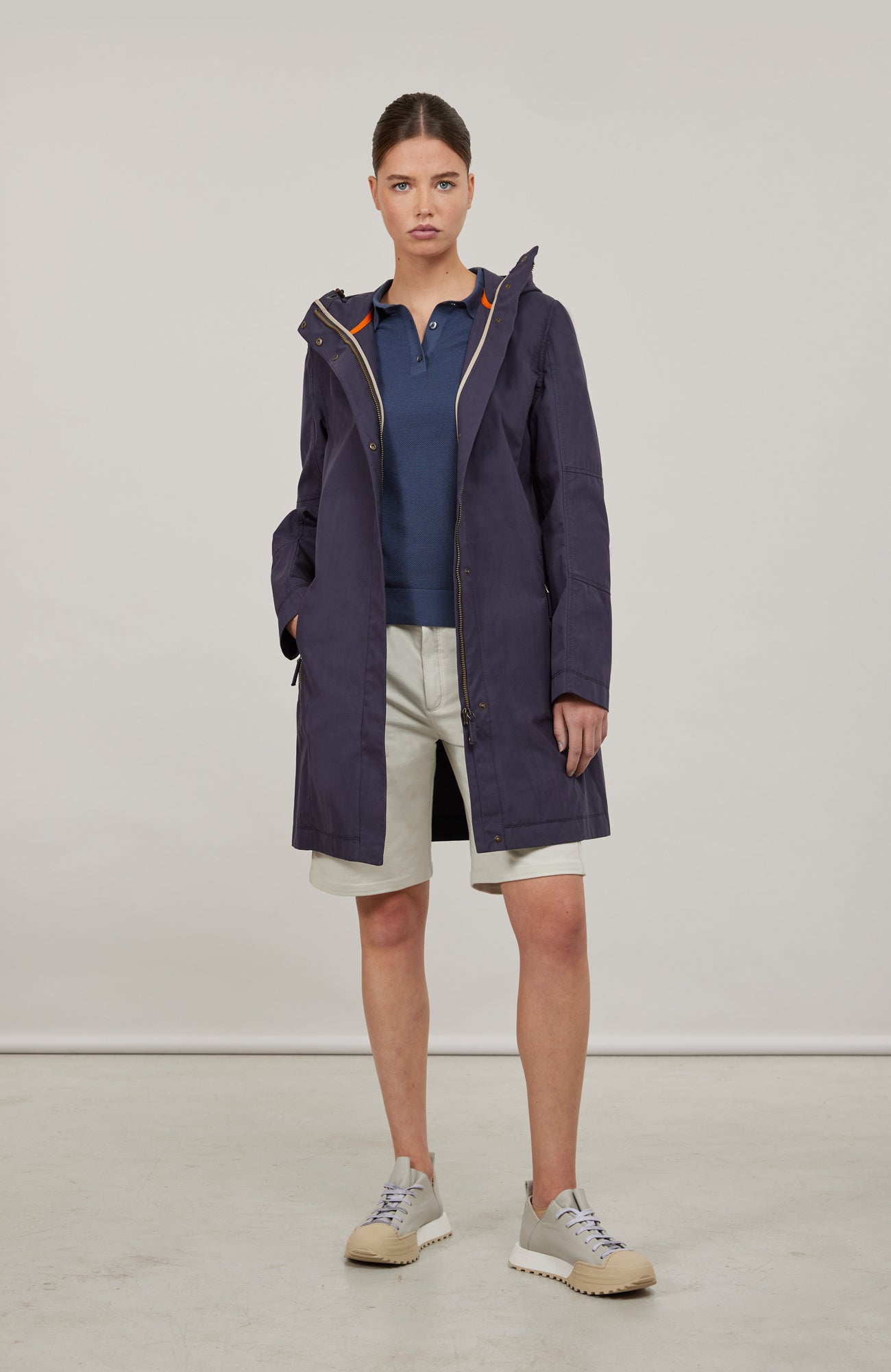 Damen-Knielanger Mantel aus Outdoor Cotton, wasser- und windabweisend, gerade Passform mit schmaler Silhouette, Stehkragen und weitenregulierbare Kapuze, Knopfleiste mit verdecktem Zwei-Wege-Zipper, Ripsband an Ärmelabschlüssen und Saum, seitliche Taschen mit markantem Zipper. In der Farbe Dunkelblau (Farbe: midnight).
