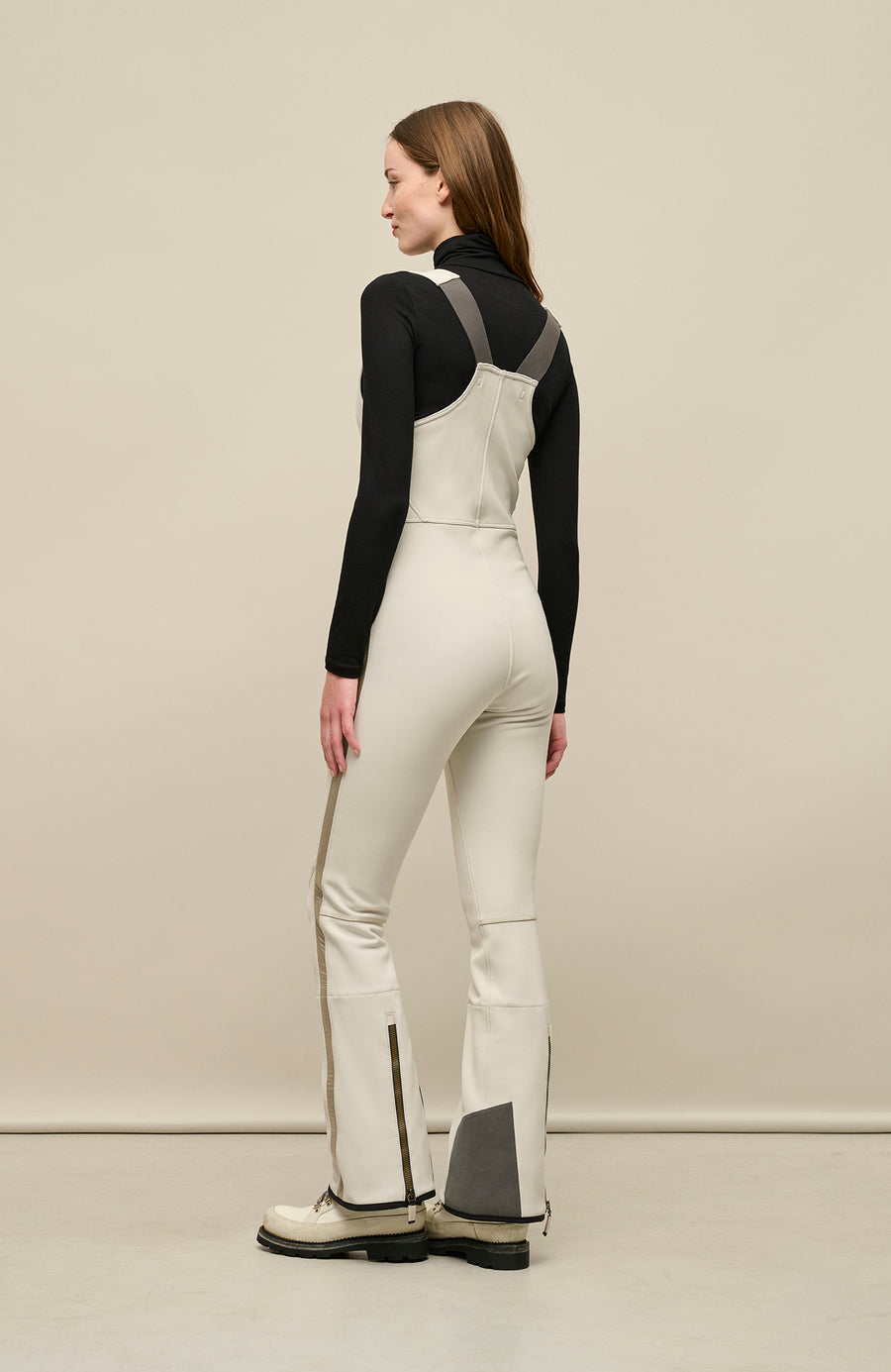 Ski-Catsuit Davina2.0-S im Latzhosen-Stil ohne Ärmel, schmaler figurbetonter Schnitt mit ausgestelltem Bein, femininer Bustier-Ausschnitt, Streifen an den Beinaußenseiten aus Alcantara-Leder, Träger hinten aus elastischem Gummi, ergonomisches Knie, markanter langer Zipper, auffallende Nähte, Seitentaschen mit Zip, Kantenschutz aus Alcantara-Leder und Schneefang. Enganliegend, feminin, betont Silhouette und Bewegungsfreiheit. In der Farbe Weiß-Beige (Farbe: sandstone)